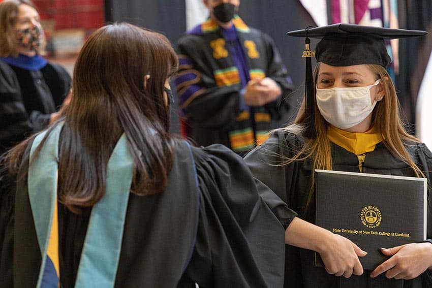 Graduate student bumping elbows with dean